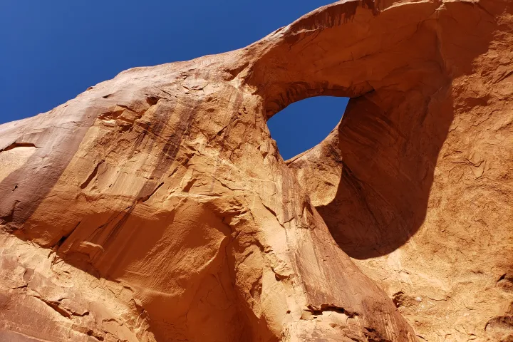 Natural stone arch against a clear blue sky.