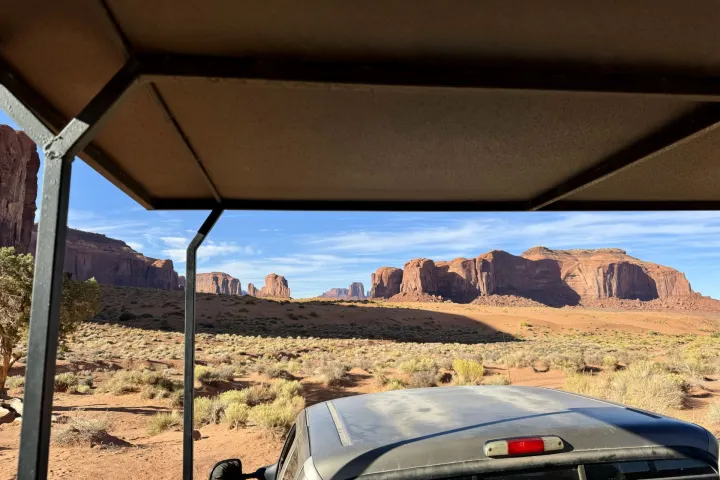 View from under a canopy of desert landscape with rock formations and clear sky.