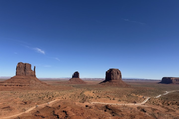 Three buttes in a desert landscape under a clear blue sky.
