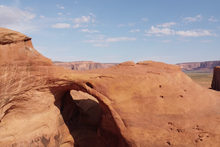 Natural arch rock formation in desert landscape under blue sky.
