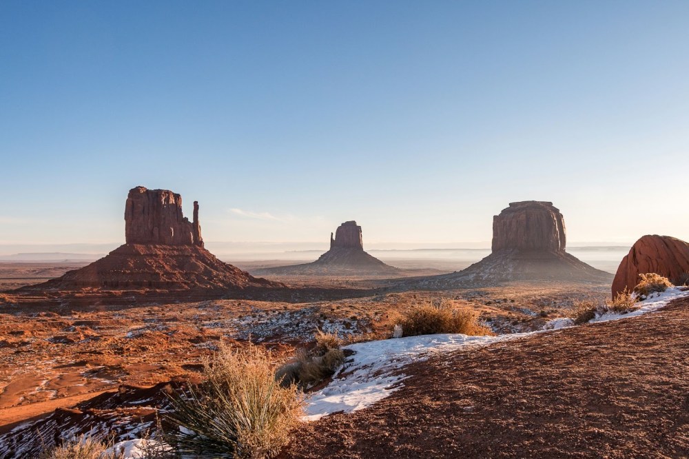 Desert landscape with three large rock formations under a clear blue sky.