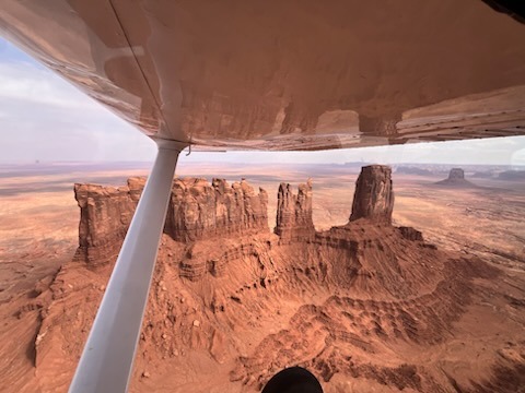 Aerial view of desert rock formations from under an aircraft wing.