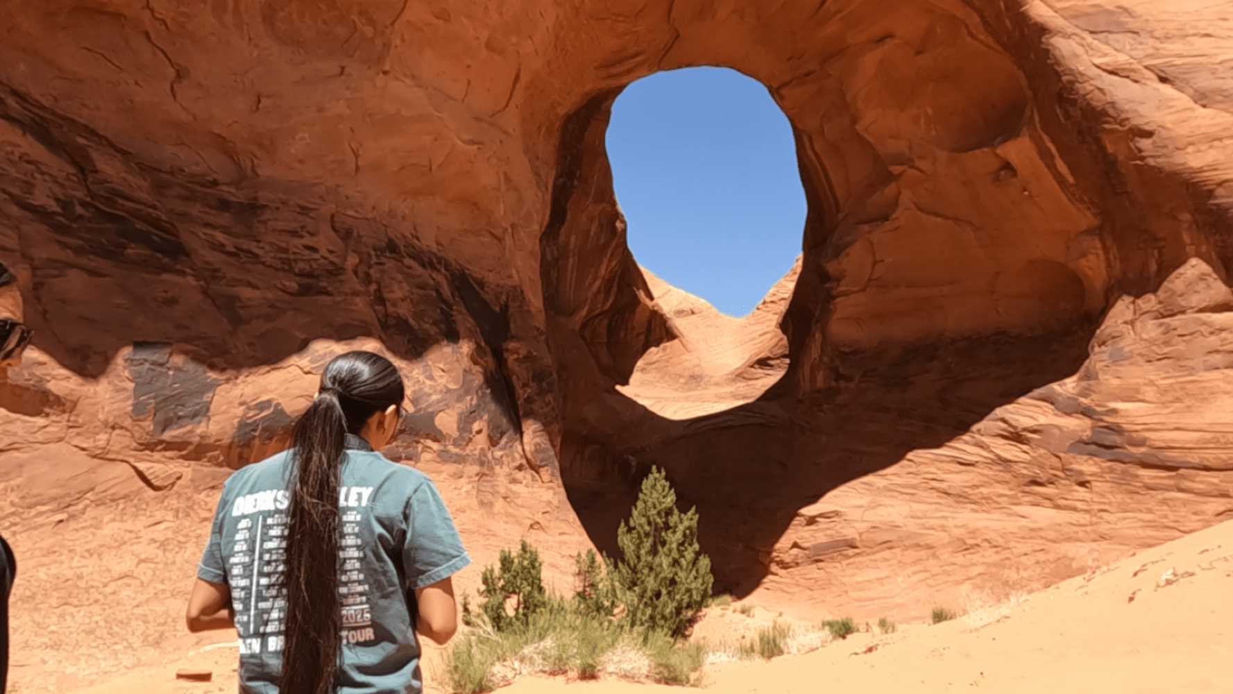 Person in desert canyon with large circular rock formation.