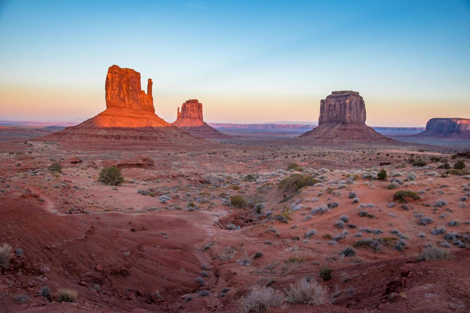 Desert landscape with rock formations at sunrise, clear sky.