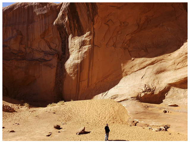 Person standing in a desert landscape with large rock formations.
