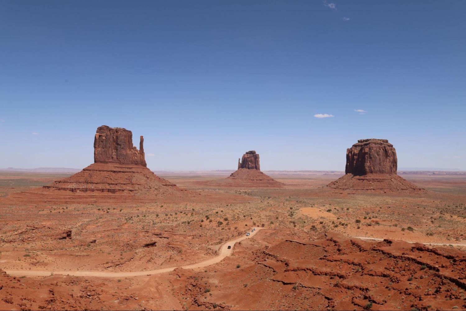 Three large rock formations in a desert landscape under a clear blue sky.